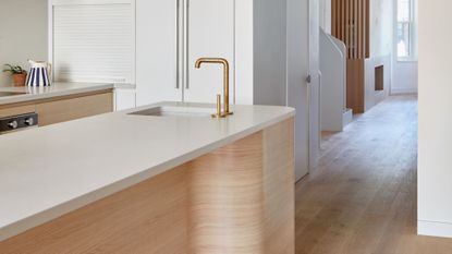 kitchen with island with white marble top and oak curved base