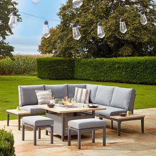 garden area with dining table and corner bench with cushions and hanging light bulbs