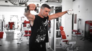 Trainer in UP Fitness On Demand workout app demonstrates lateral raise exercise