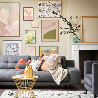 Living room feature wall with picture gallery in pastel shades, and a grey sofa with cushions and a throw