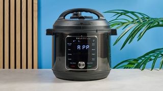 a black smart home enabled wi-Fi instant pot with a touchscreen and a 6QT inner pot is photographed against a blue background