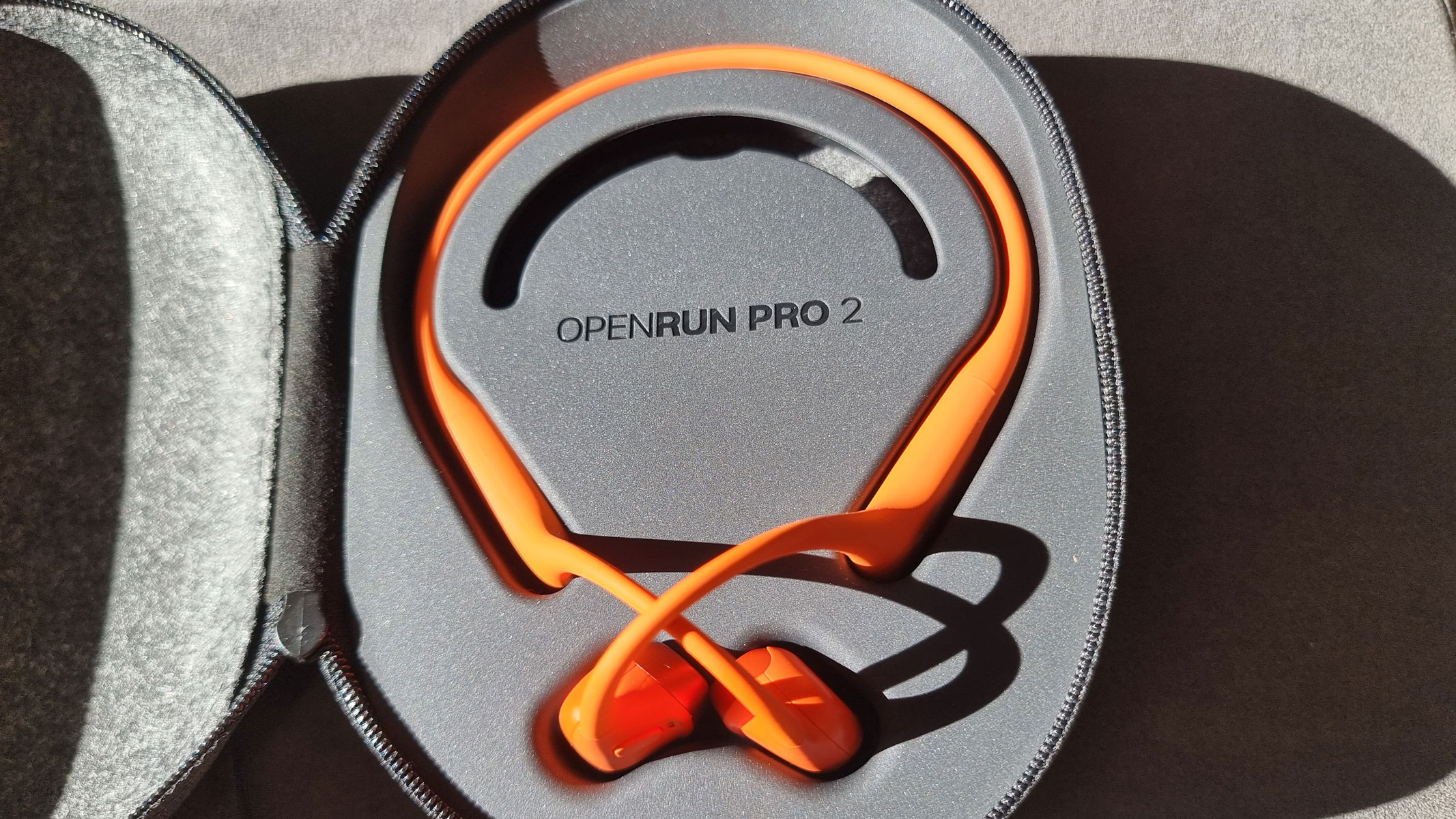 Orange Shokz OpenRun Pro 2 bone conduction headphones in an open carrying case