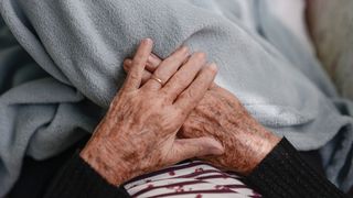 Hands of an elderly woman resting on a blanket