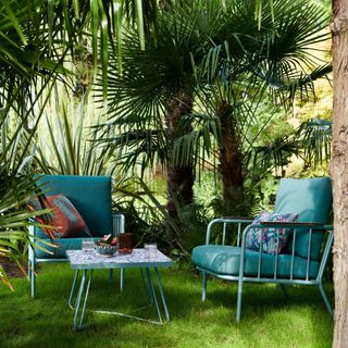 Blue metal chairs with cushions and small coffee table in garden