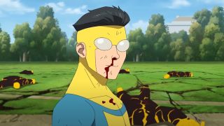 Still from the adult animated superhero T.V. show Invincible. Here we see 17-year-old superhero Invincible. He has short black hair slicked back. He has opaque lens over his eyes. He is wearing a skin-tight yellow suit with blue/green shoulders and dark gray arms. He is bleeding from the nose and it is dripping onto his clothes. In the background is a tree-lined field with 5 knocked out monsters.