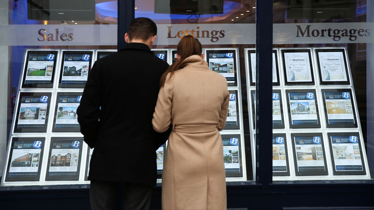 People looking in an estate agent&amp;#039;s window