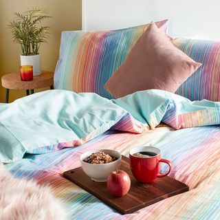 bedroom with primark rainbow stripe bedding and coffee tray on bed