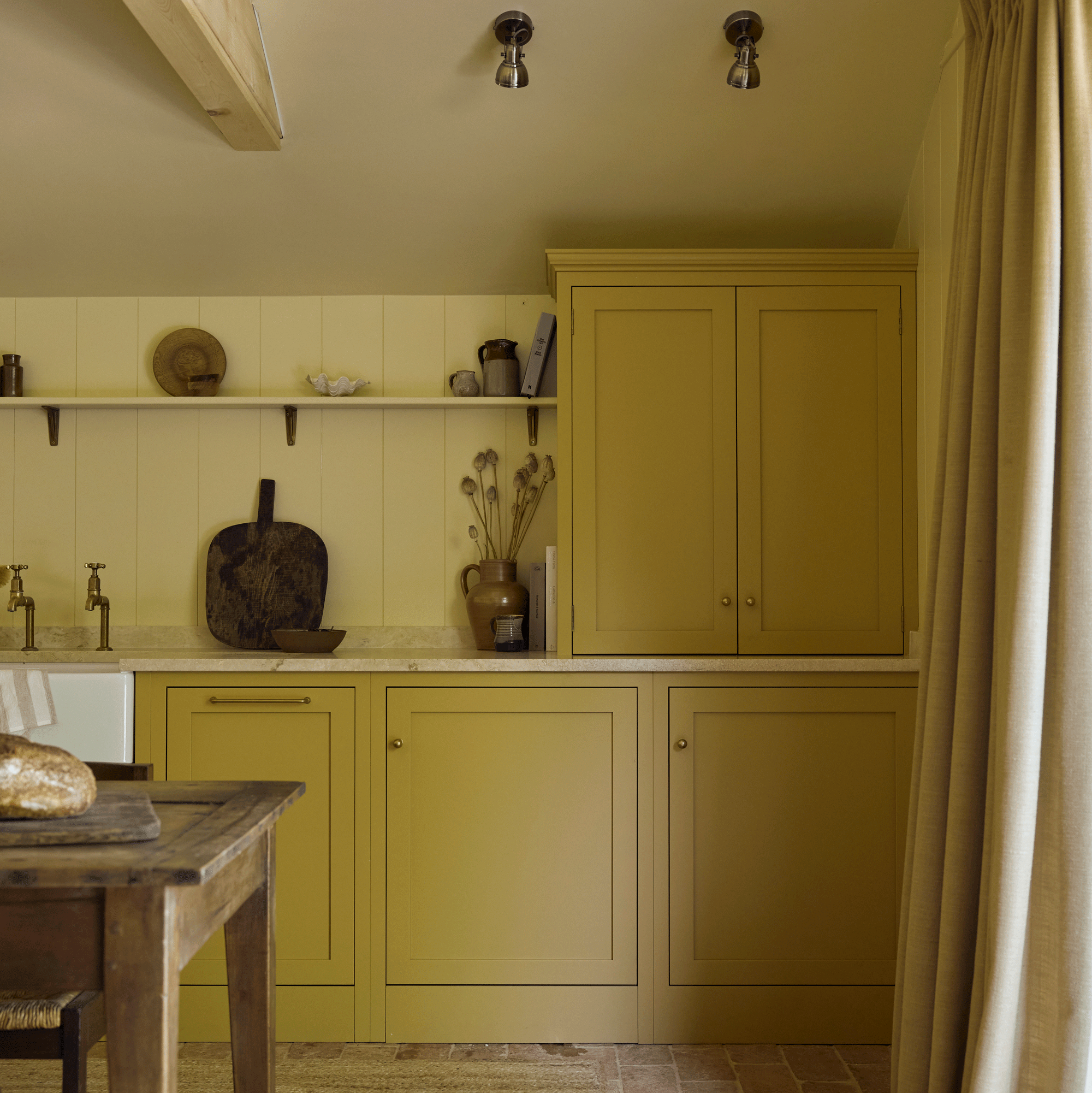an open plan kitchen diner with yellow cabinets and a reclaimed dining table