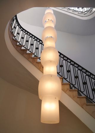 Chute Chandelier (prototype) (2021), custom designed by Philippe Malouin for the space, drops two floors down the gallery’s stairwell alongside an ornate, cast iron and marble oval staircase