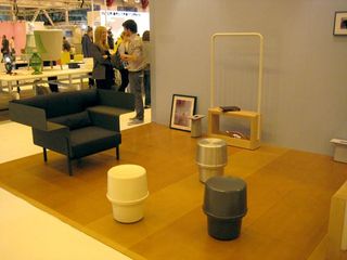 Multiple furniture pieces displayed on a wooden platform with focus on the wooden stand photographed against a blue wall