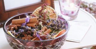 homemade potpourri in a glass bowl on a table to suggest how to make your house smell good for less