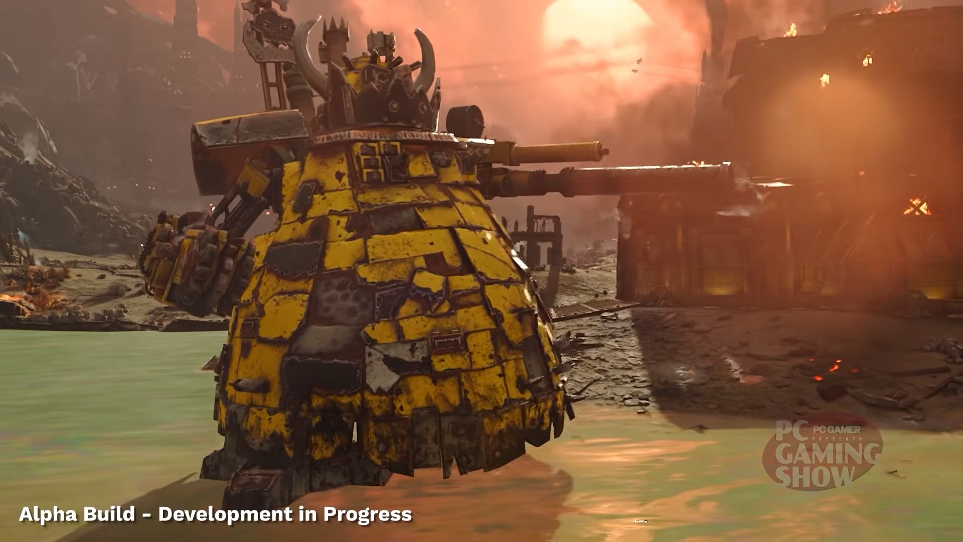 A massive, armored yellow mech with horns and battle-worn textures stands in a desolate landscape. "Alpha Build - Development in Progress" is in white text.