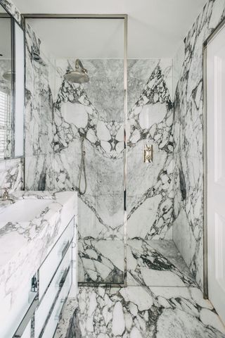 A marble walk in shower next to a marble vanity