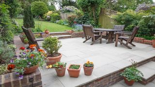 A patio lined with small pots, plus garden chairs and an outdoor table