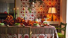 Fall tablescape with lime green and orange color theme, orange flowers on the table, green chairs and patterned linens