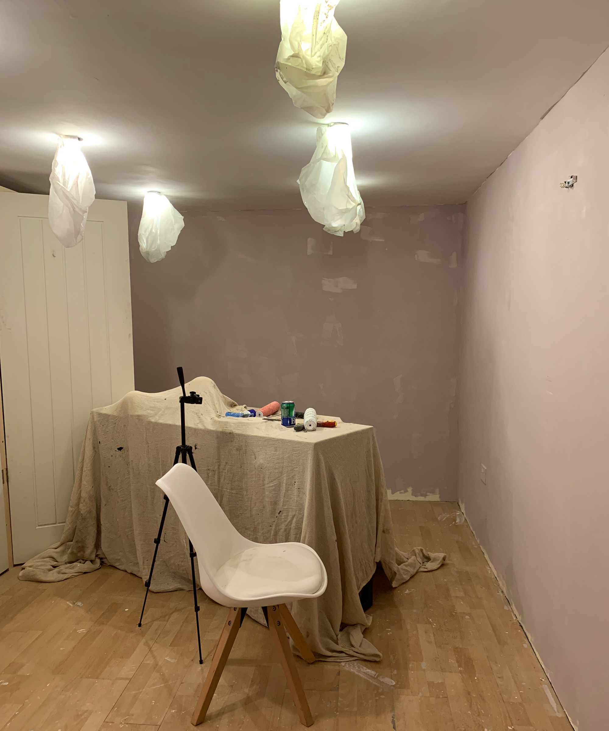 Outbuilding home office with laminate wood flooring decorated with wall paint, light fixtures have been covered with cloth