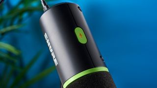 a photograph of a black and green small microphone with a muff and a USB-C connection port and a desktop stand