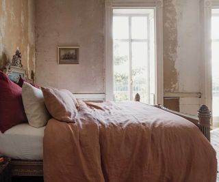 Warm Clay Linen Duvet Cover on a bed against a terracotta wall.