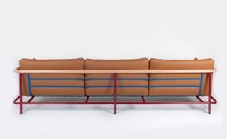 View of the brown 'Xray' sofa which has a blue and red steel frame pictured against a light grey background