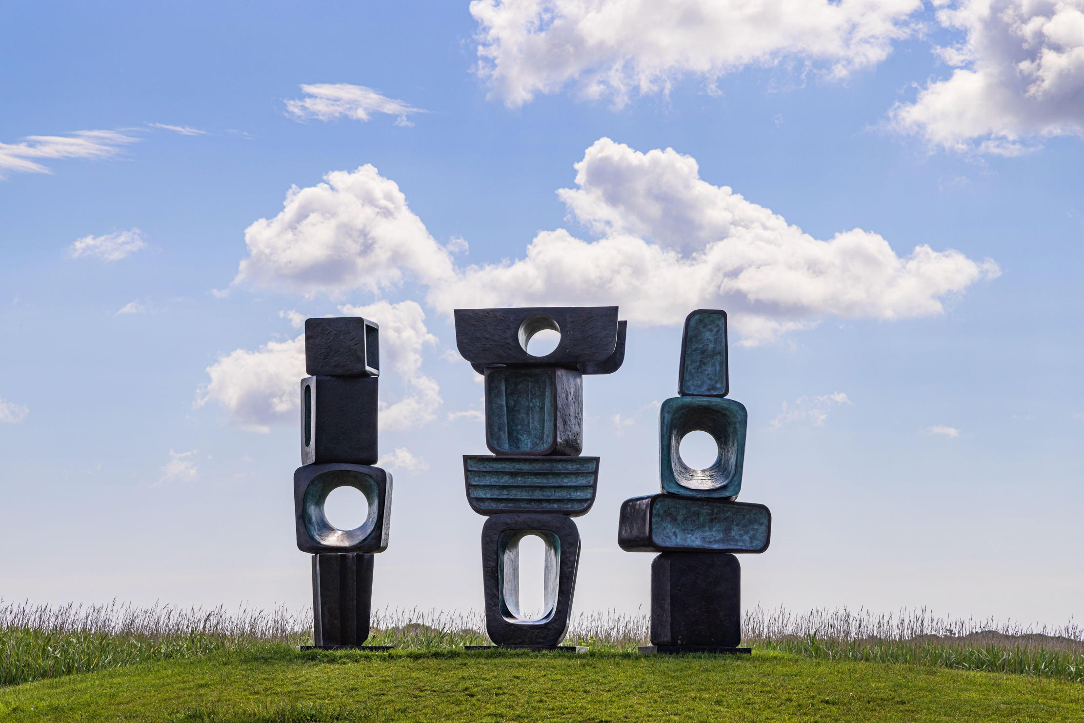 Three sculptures by Barbara Hepworth stand in a field in Suffolk
