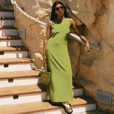 woman wearing a Faithfull x Monikh green maxi dress while standing on stairs 
