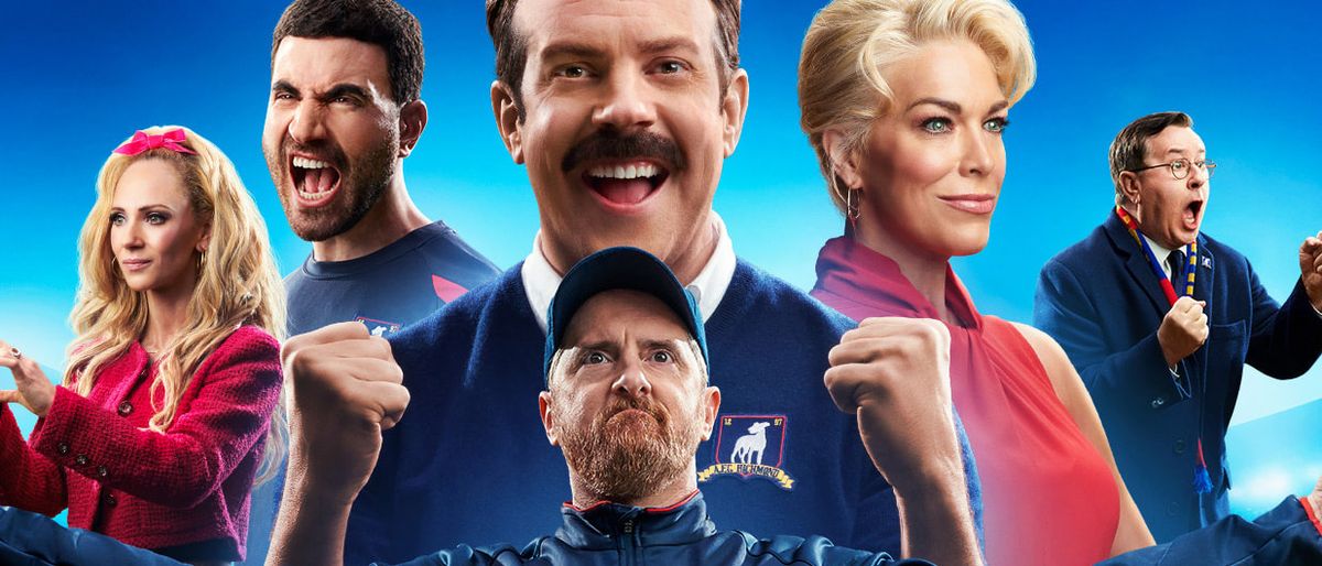 (L to R) Juno Temple as Keeley Jones, Brett Goldstein as Roy Kent, Jason Sudeikis as Ted Lasso, Brendan Hunt as Coach Beard, Hannah Waddingham as Rebecca Welton, and Jeremy Swift as Leslie Higgins in Ted Lasso season 3&#039;s poster art