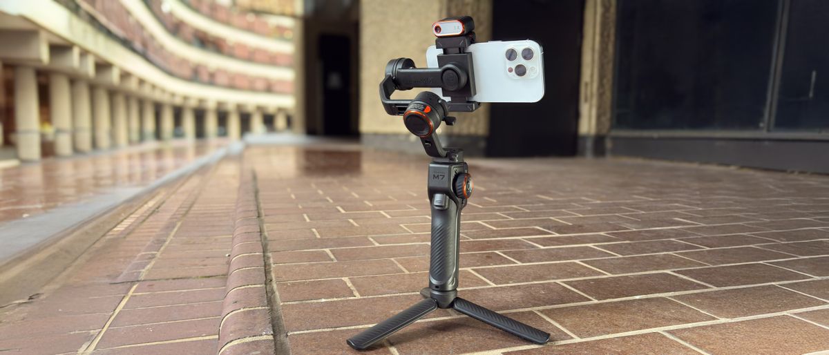 A wide shot showing the Hohem iSteady M7 mounted on its mini tripod legs