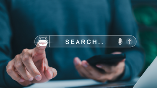 A search bar with an AI button, with a man holding a phone and pressing the button with his finger