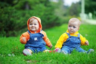 two babies sitting in grass