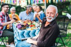 Happy smiling older man celebrating Thanksgiving day with his family at an outdoor table.