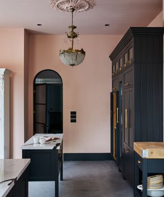 Kitchen with soft pink walls, chandelier and dark cabinets