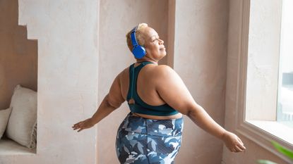 Overweight, happy woman wearing workout apparel danicing to music 