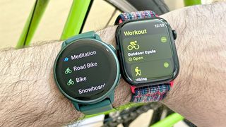 Close-up of a user's wrist wearing both the Apple Watch 10 on a multi-colored fabric strap (right) next to the Garmin Vivoactive 6 (left) on an emerald green strap 