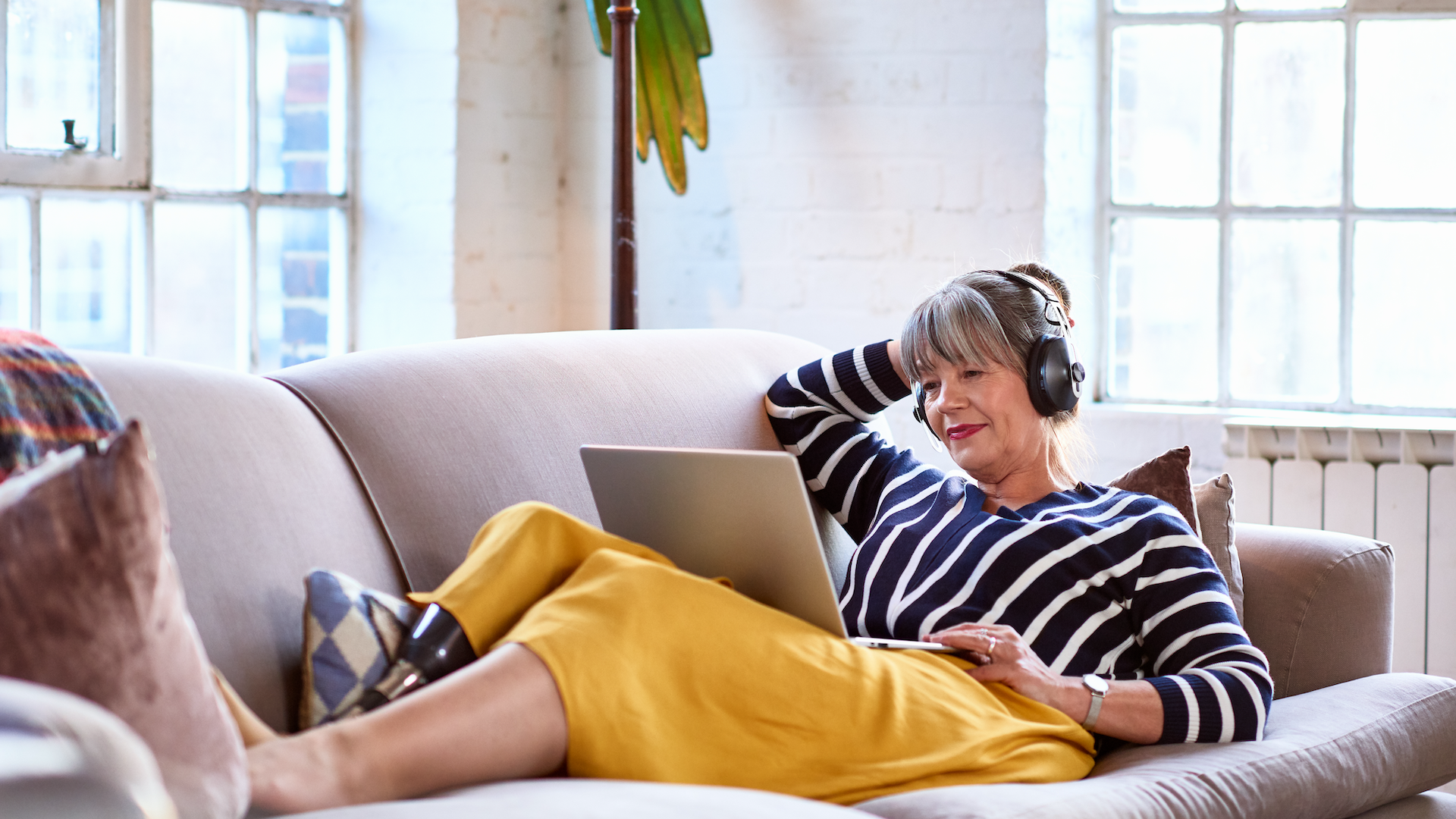 Woman sat on sofa looking at laptop