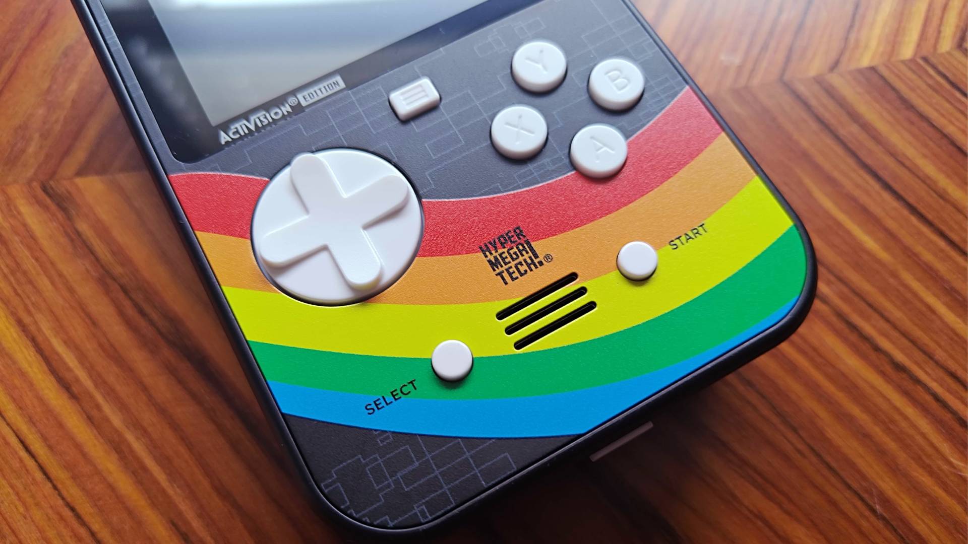 Close up of Activision Super Pocket buttons and rainbow shell on woodgrain table.