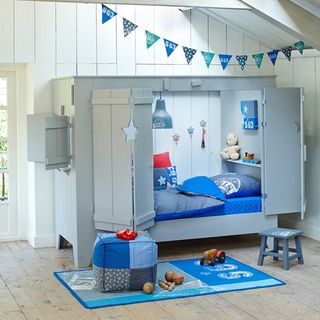 kids bedroom with wooden flooring and wall with grey cupboard cot