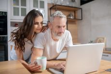 Checking e-mails. A woman hugging her husband while he is checking mails