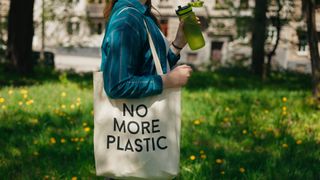 A woman carrying a tote saying no more plastic