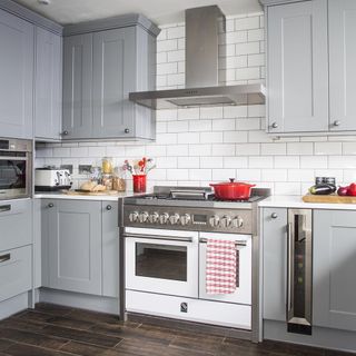 kitchen with white tiles on wall and chimney and grey cabinets