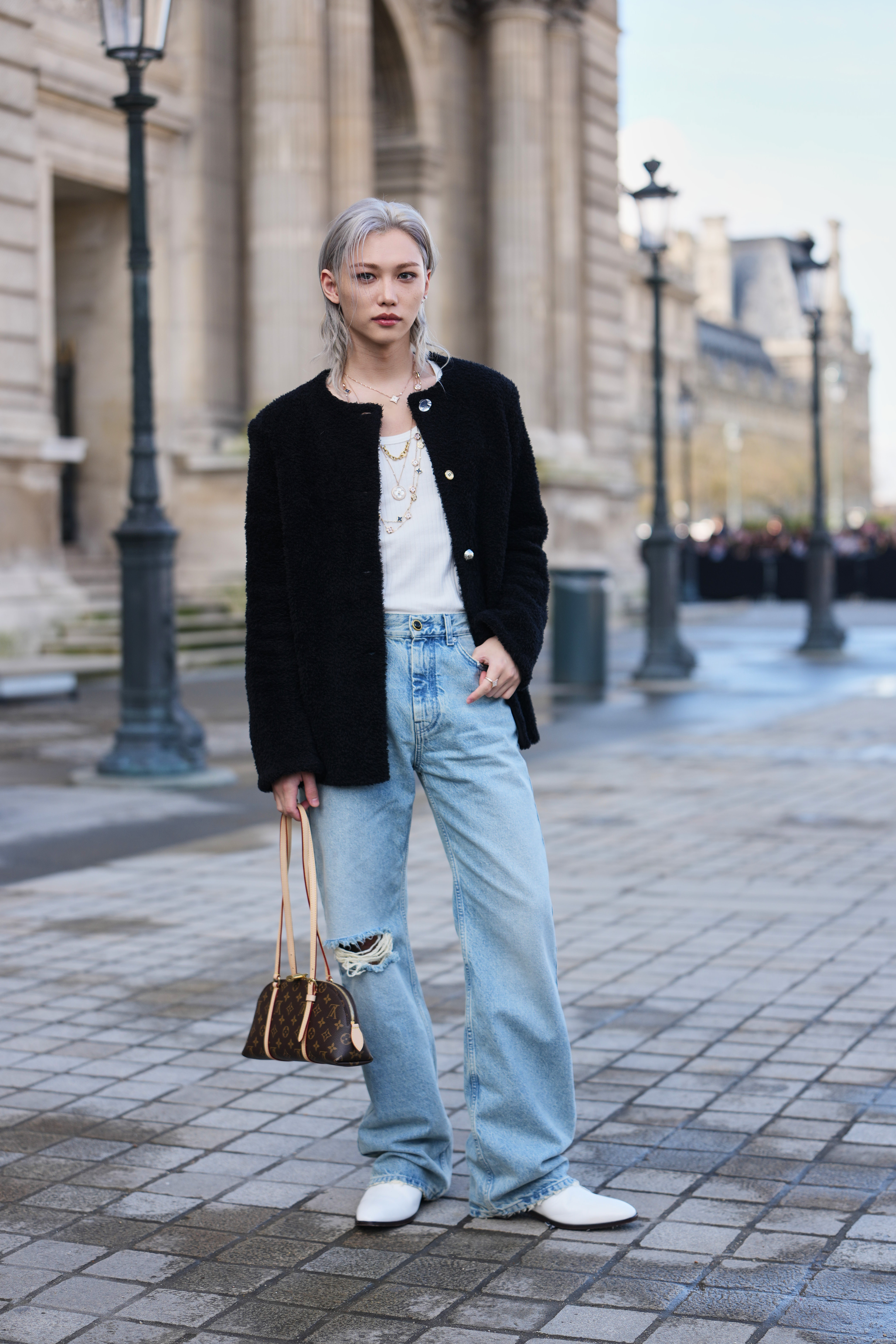 a woman wears ripped jeans with a tee and black jacket.