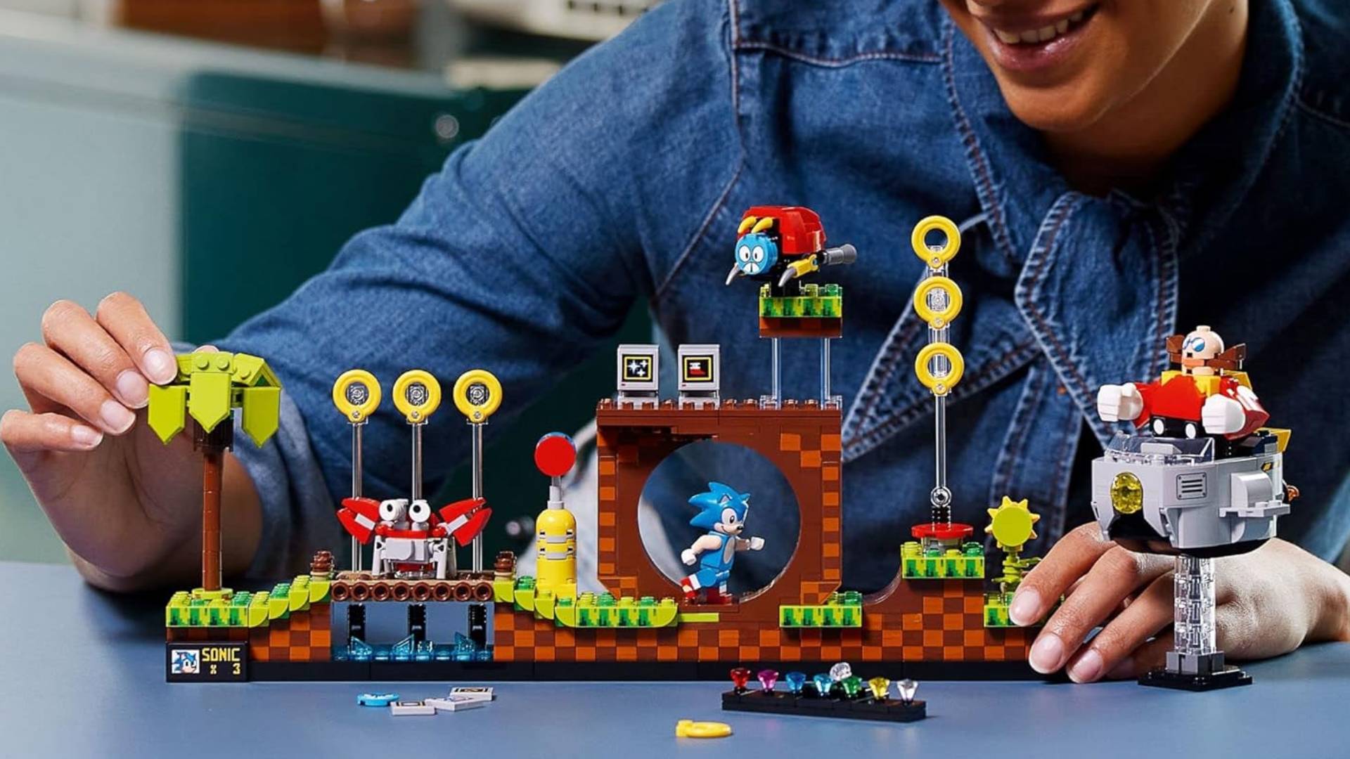 Hand putting together LEGO Ideas Sonic The Hedgehog set on blue surface