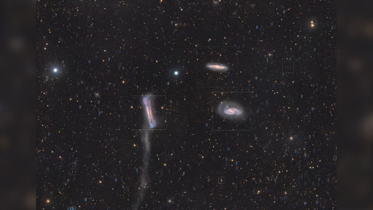 A trio of galaxies are pictured shining in deep space against a starfield dotted with more distant galaxies.