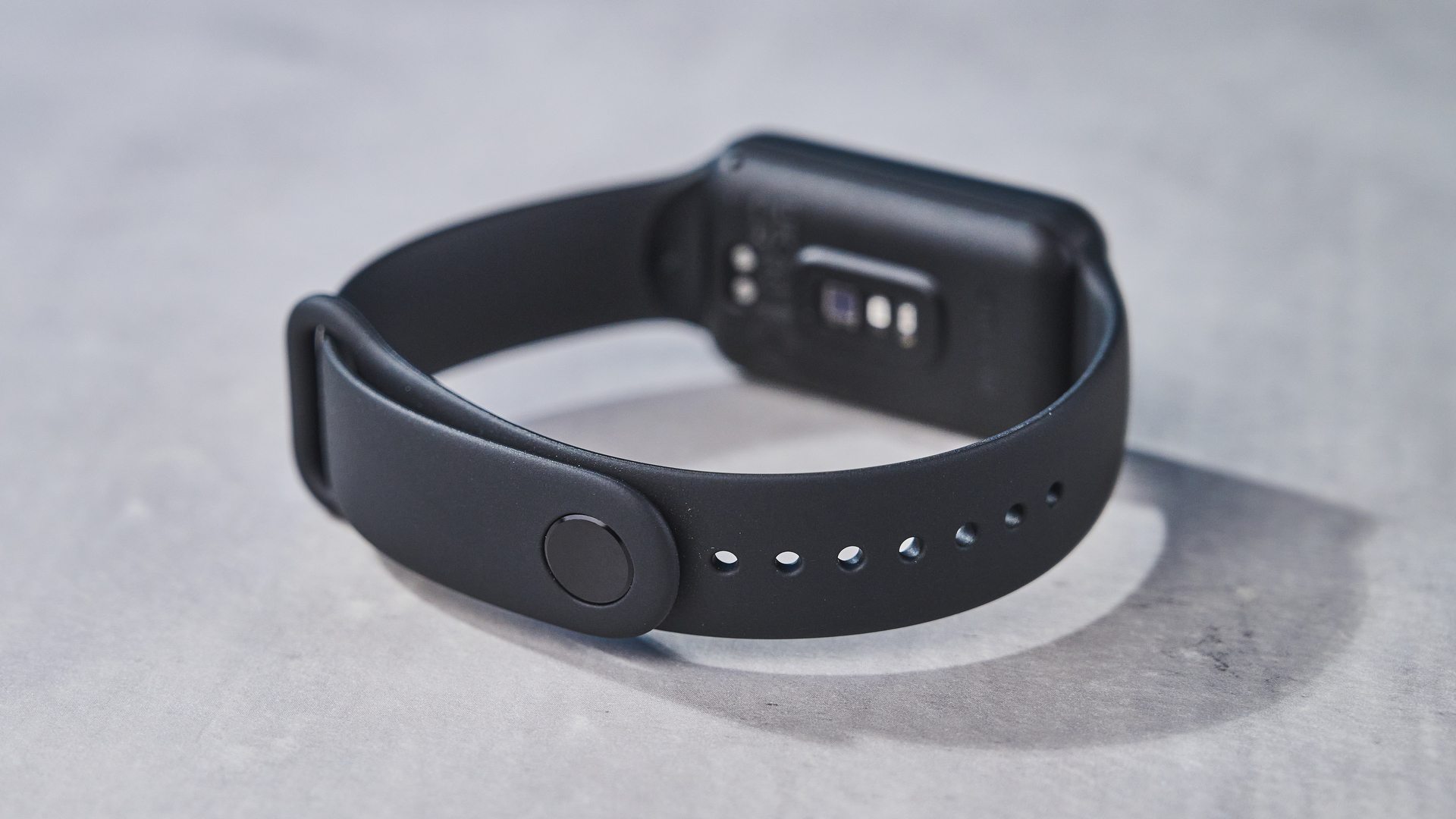 a small fitness tracker with a smooth touchscreen and TPU strap and a bright, vibrant screen showing activity types and a heart rate monitor on the underside