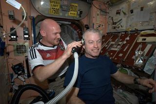 German astronaut Alexander Gerst shaves NASA astronaut Steve Swanson's head after the United States fell to Germany in a World Cup game on June 26, 2014.