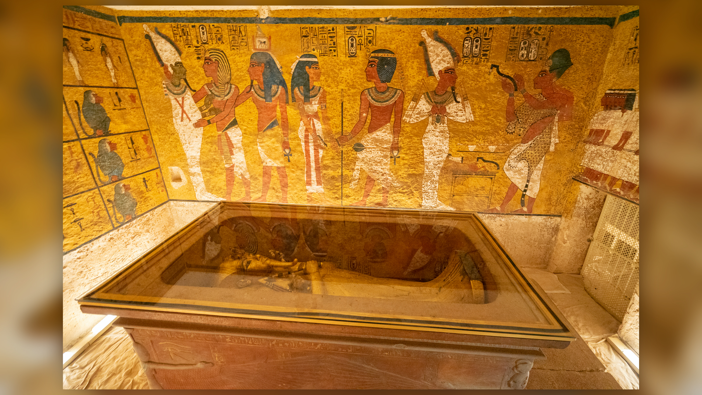 Photograph of the tomb of Pharaoh Tutankhamun in the Valley of the Kings in Luxor. The coffin is placed in the center of the room, with Egyptian paintings on the wall.