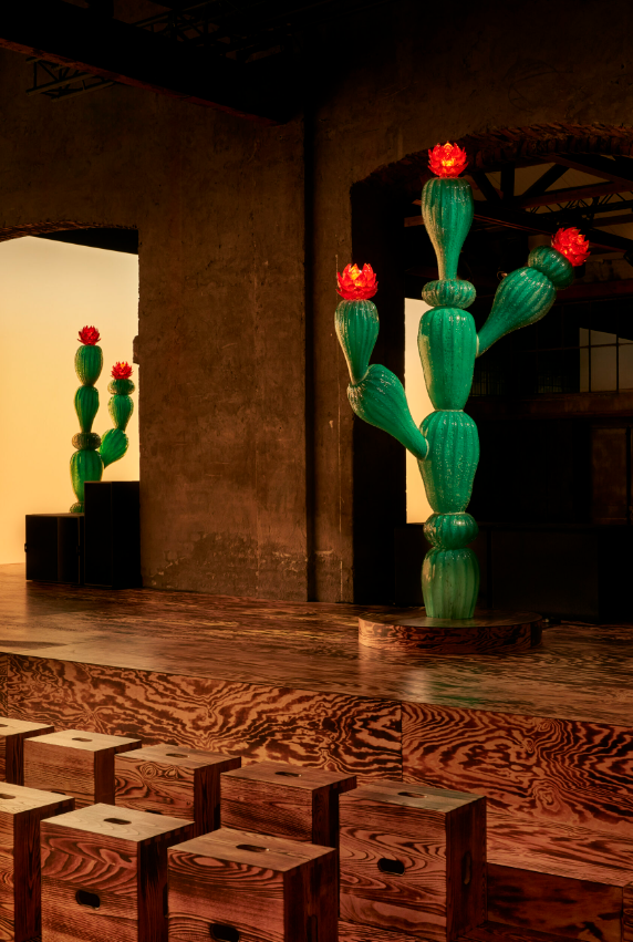 A cactus-shaped Murano glass piece illuminates a wooden fashion runway inspired by Westerns.