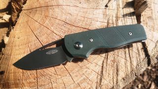 Three Rivers Atlas camping knife unfolded on log