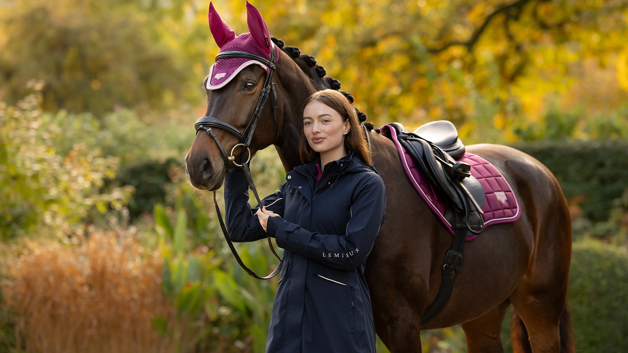 Horse wearing new AW26 Blackberry coloured saddlepad and fly veil rider wearing stormwear performance coat
