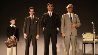 Dainton Anderson in a cap, jacket and white trousers with a satchel, Oaklee Pendergast and Calam Lynch in pin-striped suits and Jason Isaacs with grey hair, glasses and a grey suit as Archie Leach/Cary Grant at various ages in Archie
