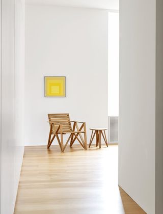 A wooden chair and table with a yellow Josef Albers painting